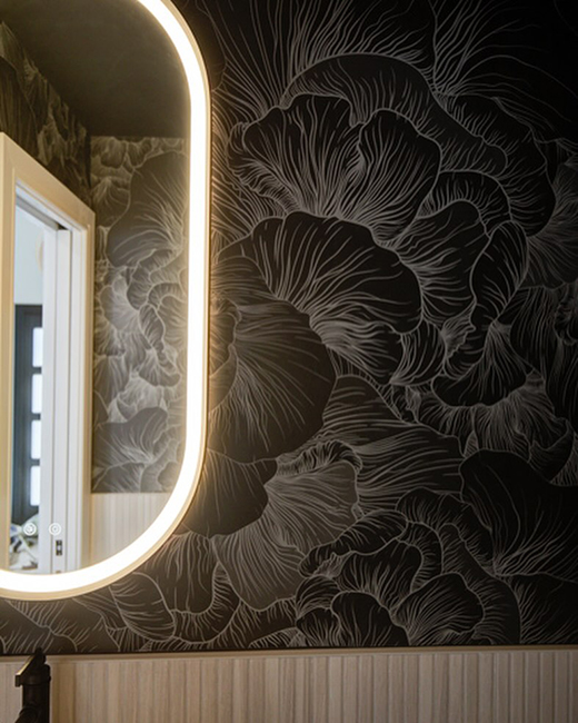 Miroir oblong encadré en or brossé Magna des Fleurco installé sur un mur d'accent à motifs floraux foncés