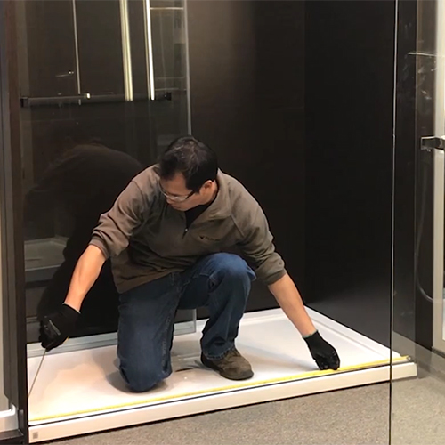 fleurco installer measuring the bottom opening of shower enclosure