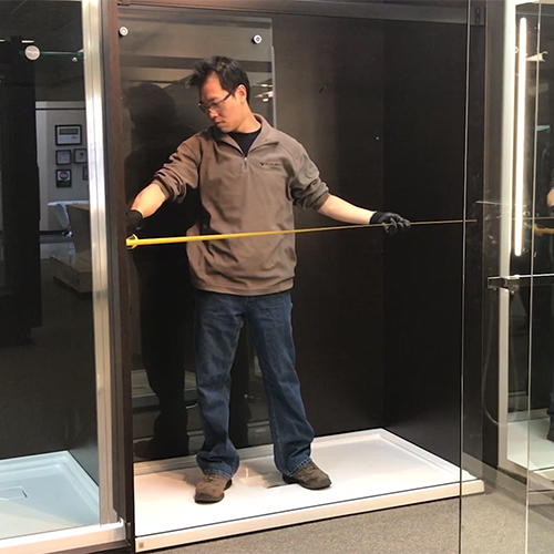 fleurco installer measuring the middle opening of shower enclosure